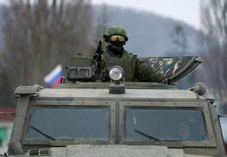 <p>Um homem armado, tido como um militar russo, em um veículo blindado de transporte de pessoal (VBTP) perto de uma unidade militar da Ucrânia em Perevalnoye</p>