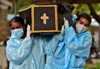 Voluntários Akshaya (D), 22, e Esther Mary, 41, carregando um caixão com corpo de vítima de Covid-19 em Bengaluru, Índia
18/5/2021 REUTERS/Samuel Rajkumar