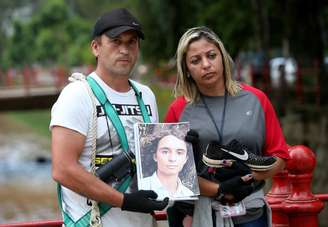 Leandro da Rocha, pai do adolescente desaparecido Gabriel da Rocha, e a madastra do garoto, Luciana, mostram a foto de Gabriel e um tênis que supostamente seria dele e foi encontrado durante as buscas