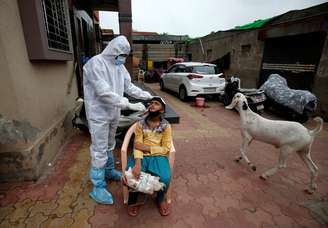 Profissional médico, utilizando equipamentos de proteção, testa um garoto para o coronavírus na Índia. 24/07/2020. REUTERS/Amit Dave. 

