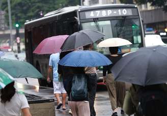 Pedestres caminham com guarda-chuva em tarde chuvosa na Avenida Paulista.