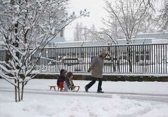 <p>Mãe usa trenó para puxar seus filhos em rua coberta pela neve em Budapeste, na Hungria, no começo da primavera no Hemisfério Norte</p>
