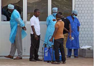 <p>Uma equipe médica recebem pacientes suspeitos de serem portadores do vírus Ebola na entrada da emergência de um hospital em Conakry, Guiné, em 29 de março</p>