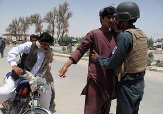 <p>Policial afegão revista passageiros em um posto de controle na província de Helmand, em 25 de junho, quando mais de 800 insurgentes talibãs lançaram uma grande ofensiva no sul do Afeganistão para tentar ganhar território recentemente desocupado pelas tropas dos EUA</p>