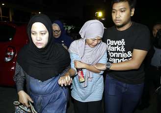 A mãe de um membro da tripulação Trigana Air avião desaparecido (ao centro) chora enquanto anda fora do escritório principal Trigana Air, em Jacarta, Indonésia