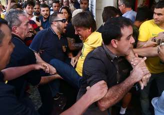 O candidato à Presidência da República pelo PSL, Jair Bolsonaro (de camiseta amarela), é socorrido após ser esfaqueado durante ato de campanha em Juiz de Fora (MG), nesta quinta-feira, 06. O presidenciável foi levado para o hospital.