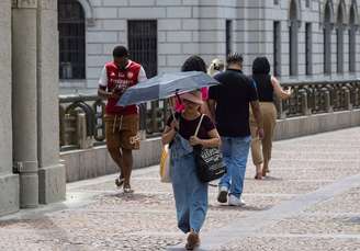 Mulher utiliza sombrinha para se proteger do sol forte no Vale do Anhangabaú, região central de São Paulo.