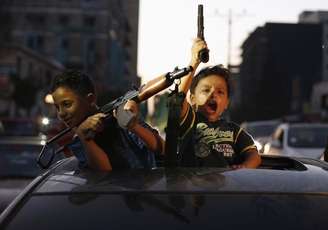 Crianças palestinas seguram armas em Gaza para comemorar o que dizem ter sido vitória sobre Israel após um cessar-fogo.   26/8/2014.
