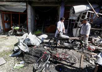 Vendedores recuperam pertences em frente  a loja após explosão de carro-bomba em Cabul