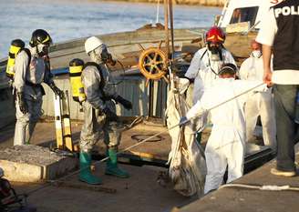 <p>Bombeiros recuperam um dos corpos encontrados em um barco de pesca que estava cheio de imigrantes, depois que a embarcação foi rebocada pela Marinha italiana no porto siciliano de Pozzallo, em 1º de julho</p>
