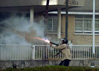 Oficial da Guarda Nacional Bolivariana atira gás em manifestantes durante protesto em Caracas, neste sábado, 8 de março