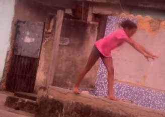 A pequena Emanuelly fez um exercício de trave em uma mureta na rua