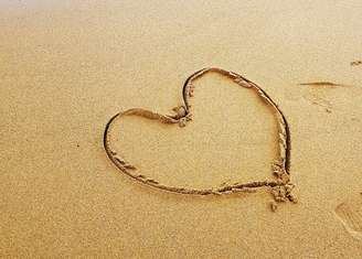 Imagem de um coração desenhado na areia 