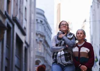 Pedestres caminham na Rua 15 de Novembro no centro de São Paulo em dia de frio.