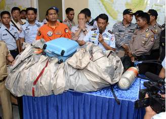Membros da Força Aérea da Indonésia mostram mala e partes do avião da AirAsia que foram encontradas na Mar de Java