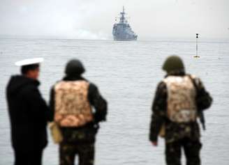 <p>Membros da Marinha ucraniana olham navio russo flutuando sobre as água próximas à baía de Sebastopol, em 04 de março</p>