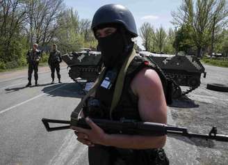 <p>Soldados ucranianos montam guarda perto de um veículo blindado em um posto de controle fora da cidade de Slaviansk, em 27 de abril</p>