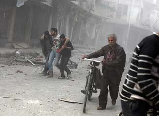 <p>Um homem é socorrido após um ataque aéreo realizado por forças do regime sírio na cidade de Douma, a nordeste da capital Damasco, um reduto da oposição desde o início da revolta contra o presidente Bashar al-Assad, em 13 de abril de 2014</p>