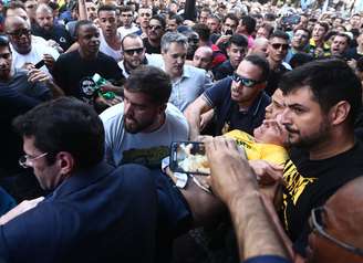 O candidato à Presidência da República pelo PSL, Jair Bolsonaro (de camiseta amarela), após ser esfaqueado durante ato de campanha em Juiz de Fora (MG), nesta quinta-feira, 06. 