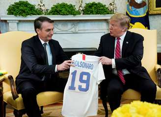 Presidente dos EUA, Donald Trump, entrega camisa do time de futebol feminino do país ao presidente brasileiro Jair Bolsonaro em encontro realizado na Casa Branca