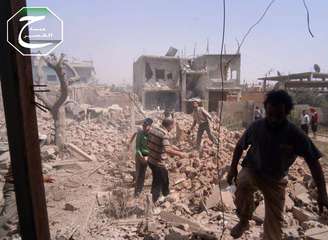 <p>Imagem feita pela organização rebelde Qusair Lens e cedida à agência <em>AP</em> mostra sírios inspecionando os destroços de prédio destruído no ataque, em Qusair</p>