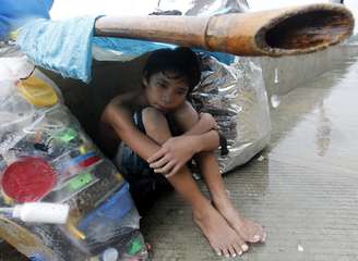 Menino improvisa cobertura para se esconder da chuva em Manila