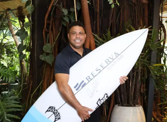 Ronaldo Fenômeno com prancha de surfe em evento para anunciar parceria com clube de luxo com piscina de ondas