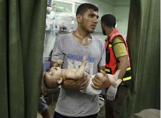 Bebê palestino é carregado em hospital após ser retirado de escola da ONU usada como abrigo por refugiados palestinos que foi atacada por artilharia na Faixa de Gaza. 24/7/2014.
