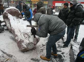 <p>Pessoas usam martelos para destruir a estátua de Vladimir Lênin em Kiev</p>