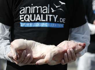 <p>Um ativista do grupo de direitos dos animais 'animalEQUALITY ' segura um leitão morto, ao participar da vigília solene com animais que morreram em indústrias de alimentos e laboratórios experimentais, para protestar contra a pecuária intensiva em Berlim</p>