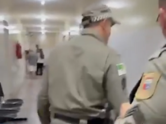 Um dos policiais aparece empurrando violentamente o homem de volta para a cadeira onde ele estava sentado