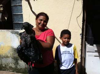 <p>Luzineide carrega o "xodó" Neguinho ao lado de um de seus filhos</p>