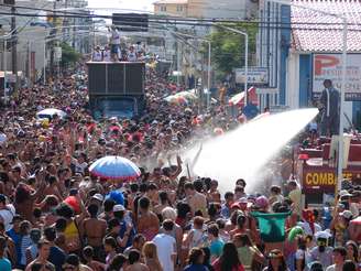 <p>Bombeiros jogam água na multidão para refrescar os foliões, no Navegay, uma das maiores festas de Carnaval da região</p>