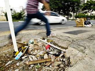 <p>Pedestre salta por cima de um buraco na calçada da avenida Engenheiro Luís Carlos Berrini, em São Paulo</p>