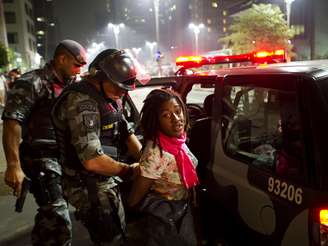 <p>Manifestante é presa por policiais militares durante o protesto na noite de quinta-feira</p>