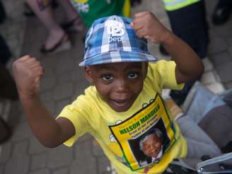 Criança sul-africana gesticula enquanto aguarda na fila do velório de Mandela no Union Buildings, sede do governo em Pretória