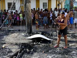 <p>Moradora recolhe destroços em meio à deflagração do confronto entre policiais e bandidos no Rio</p>