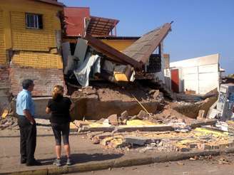 <p>Pessoas olham para uma casa danificada pelo forte terremoto de magnitude 8,2 que atingiu a costa do Pacífico do Chile, em Iquique, norte do país, em 2 de abril</p>