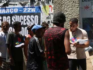 A imagem mostra um homem entrevistando pessoas em situação de rua.