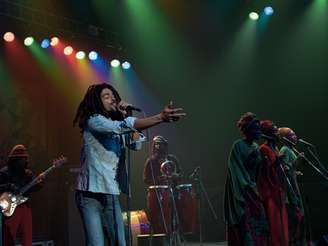A imagem mostra uma cena do filme de Bob Marley, que teve pré-estreia no Brasil. Na foto é possível ver o intérprete de Bob Marley no palco.