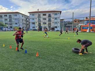 Parte nobre da favela do Arará, na entrada, perto do asfalto, com campinho de grama sintética e conjunto habitacional.