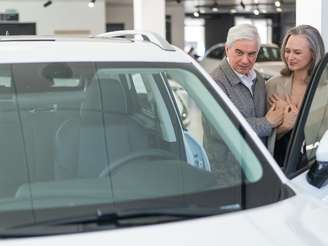 Casal de idosos comprando carro na concessionária