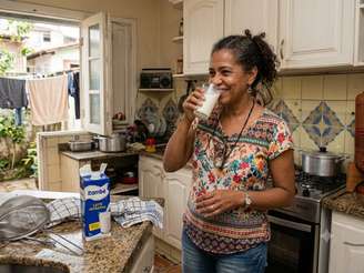 Mulher brasileira bebendo um copo de leite na cozinha
