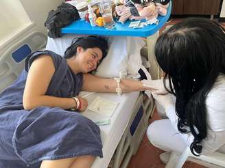 Melisa deitada na maca de um hospital conversando com um profissional de saúde