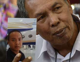 <p>O pai de Mohd Selamat mostra a foto do filho que estava a bordo do avião desaparecido. A polícia do país investiga possível participação do engenheiro na mudança de rota do Boeing</p>