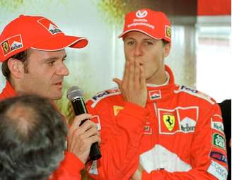 Rubens Barrichello fala ao microfone ao lado de Michel Schumacher em foto de 26 de março de 2000. Dupla correu pela Ferrari no GP de Interlados àquele ano.