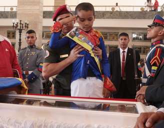 O corpo de Chávez continua sendo velado na Academia Militar; na imagem, um menino vestido como o libertador Simón Bolívar bate continência ao presidente morto