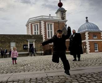 Criança pula sobre linha que representa a divisão do mundo em fusos horários no Observatório Real de Londres, em Greenwich