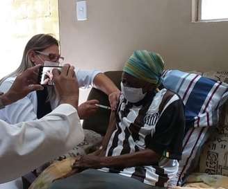 Dona Maria se vacinando contra covid-19 com a camisa do Santos (Foto: Reprodução)