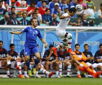 <p>Pouladi e Vrsajevic disputam bola aérea durante jogo entre Bósnia e Irã</p>